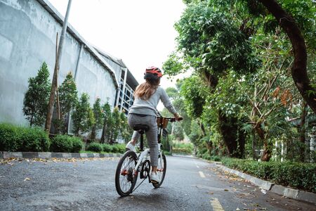 Asian young woman goes wearing a helmet to riding by folding bicycleの写真素材
