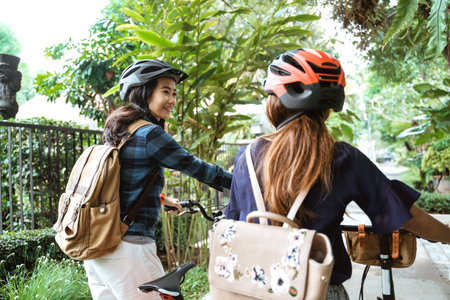 Two asian woman walking with folding bike while chatting