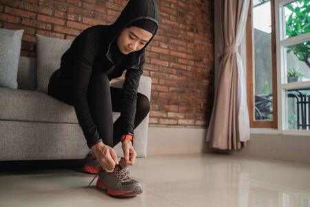 Young asian muslim women wear sports hijabs and fix shoelaces at the doorの写真素材