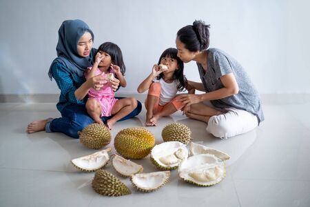 woman with kids eating durian fruitの写真素材