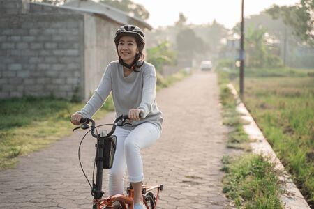 Asian women wear helmets to ride folding bikesの写真素材