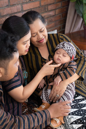 having fun of asian happy family sitting on sofa wearing javanese batik heritage