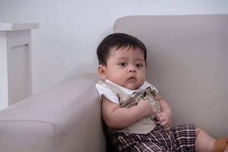 cute little boy sitting alone on couchの写真素材