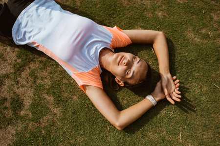 Fitness sport girl resting after intensive run laying on grass