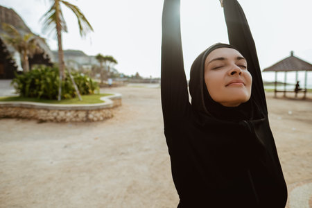 Healthy young muslim woman warming up outdoors