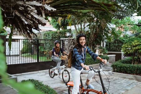 Two asian young woman wearing helmet and bags ready go to campusの写真素材