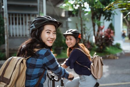Two young girl are ready go to school by folding bicycleの写真素材