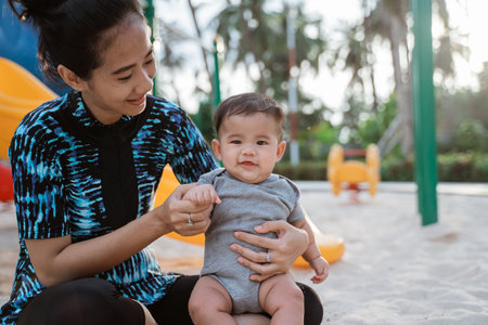 asian mother and little daughter enjoy playing in a playground