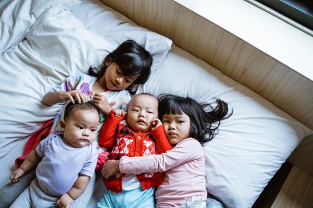 four children lie in bed hugging each otherの写真素材