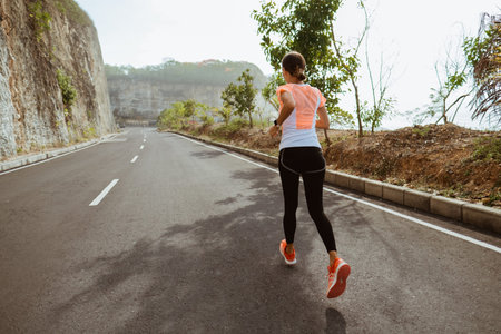 sport woman running on sideroad. fit woman jogging on empty road