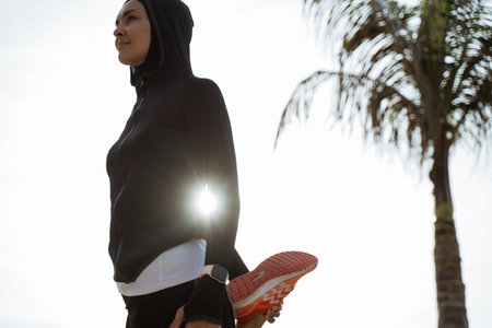 Young fitness muslim woman runner stretching legs before run
