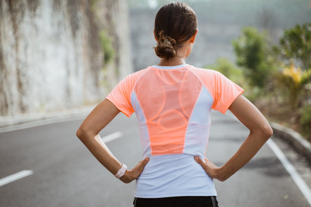 Fitness sport girl resting after intensive run, young attractive runner taking break after jogging...