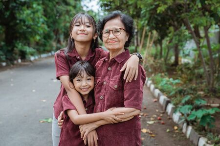 two asian granddaughters hugging their grandmotherの写真素材