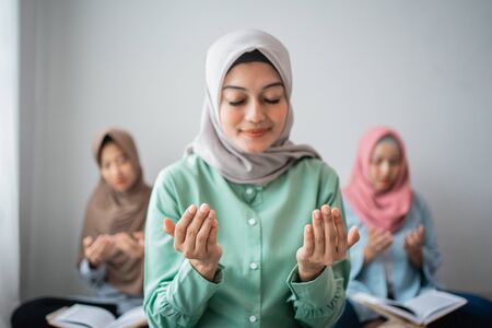 Three veiled women sit on the floor prayingの写真素材