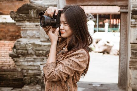 Woman photographer taking picture using cameraの写真素材