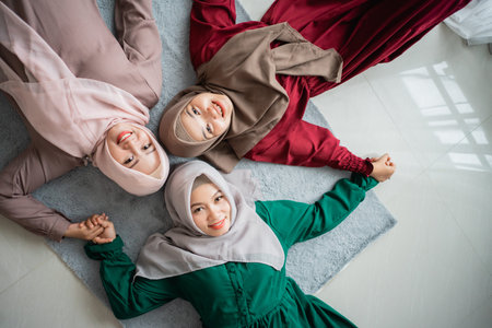 three hijab women smiled while laying on the mattress