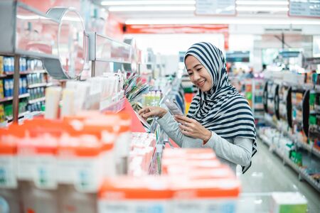 muslim asian woman shopping in grocery store supermarket buying some product