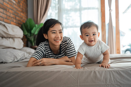 proud mother looking at her baby crawling on the bed