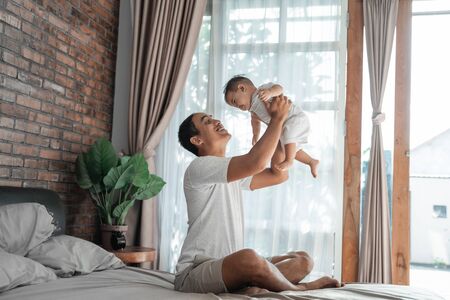 father bonding with baby. man playing with his daughter on the bedの写真素材