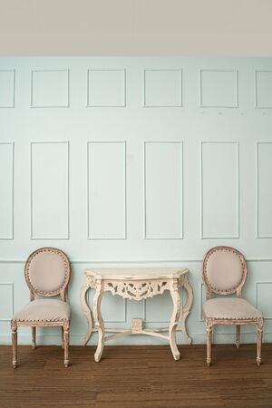 Vintage seat and classical carved wooden table on green background,elegant room with a patterned wallの写真素材