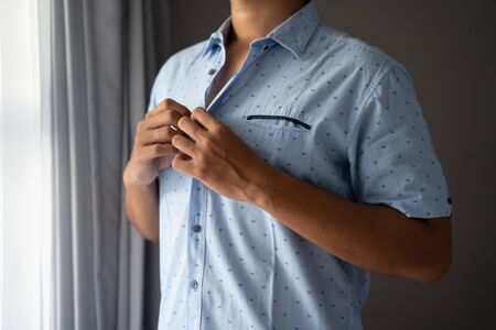 Men button blue shirts on weekdays in a roomの写真素材