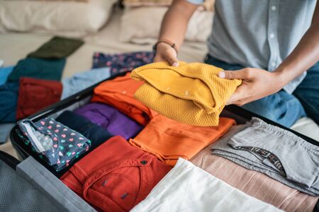 young man preparing her clothes put in the suitcaseの写真素材