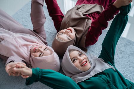 group of moslem female friends smiled while laying on the mattressの写真素材