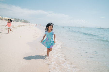 asian little girls run and laugh in the beachの写真素材