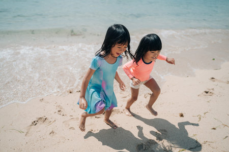 two little Asian girls playing on the beach