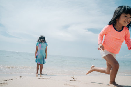 two little girls playing hide and seek on the beach