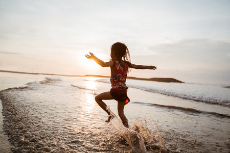 Asian little girl running and jump on the beach while playing water on a nice beachの写真素材