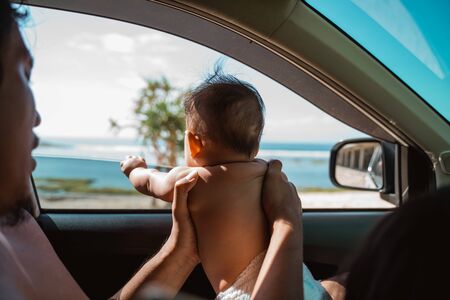 Father carries his baby to look out the car windowの写真素材