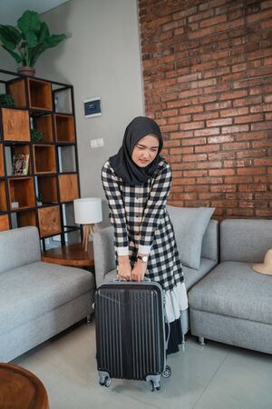 muslim woman carrying heavy suitcaseの写真素材
