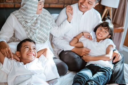asian families with their children are relaxing and joking on the bedの写真素材
