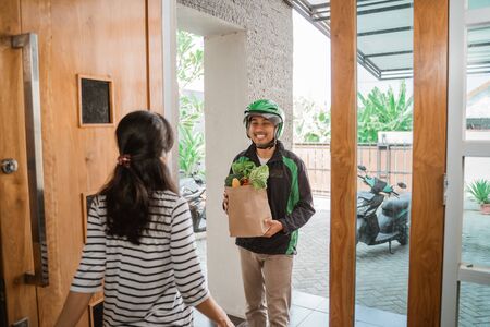 delivery boy is delivering some groceries to womanの素材 [FY310146420153]