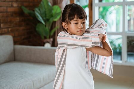 girl putting her clothes on by herselの写真素材
