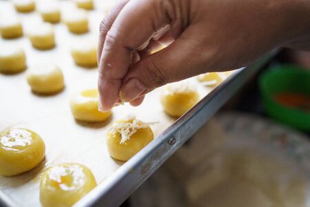 pouring some cheese on nastar pineapple tart cakeの写真素材