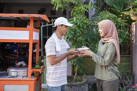 street food vendor handing a bowl of baksoの写真素材