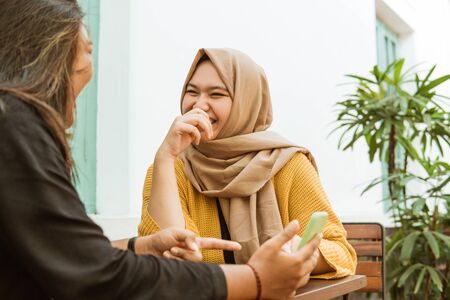 two Asian girls chatting and holding a cellphoneの写真素材