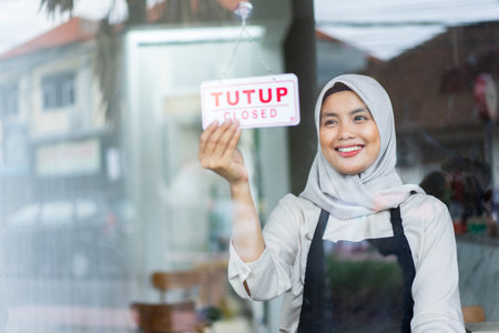 asian veiled waiter holds a closed sign board