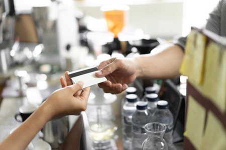 close up hand of the buyer gives a credit card to the seller to pay at the cafe