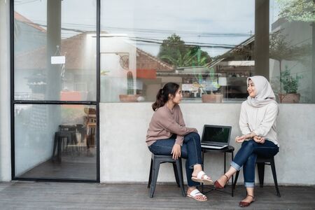 woman freelancer with friend sitting in cafeの写真素材