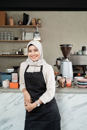 asian female waitress with lean back arm standing at workplaceの写真素材