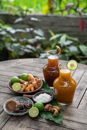 Herbal drinks of beras kencur and kunyit asam are packed in glass bottles,raw materials of white rice,rhizomes of kencur,turmeric,brown sugar,tamarind and oranges for garnishesの写真素材