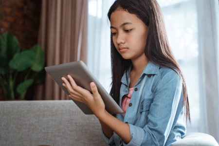 serious looking teen using tablet at home