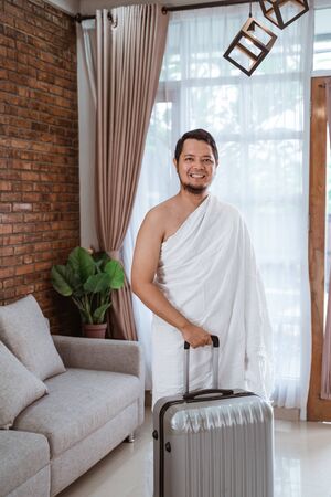 happy smiling muslim male with suitcase going for hajj isolated over white backgroundの写真素材