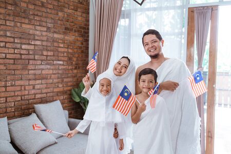 muslim umrah and hajj with family holding malaysian flagの写真素材