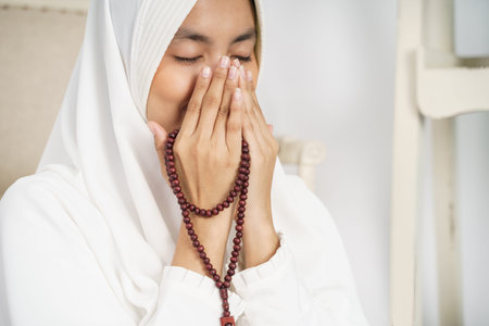 Muslim young woman praying in white traditional clothes