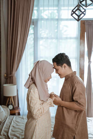 young Muslim couple smiling at each other forehead facing each other and holding handsの写真素材