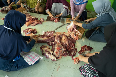 veiled adult women slice a lot of meat to be distributed after during the Eid al-Adha celebration